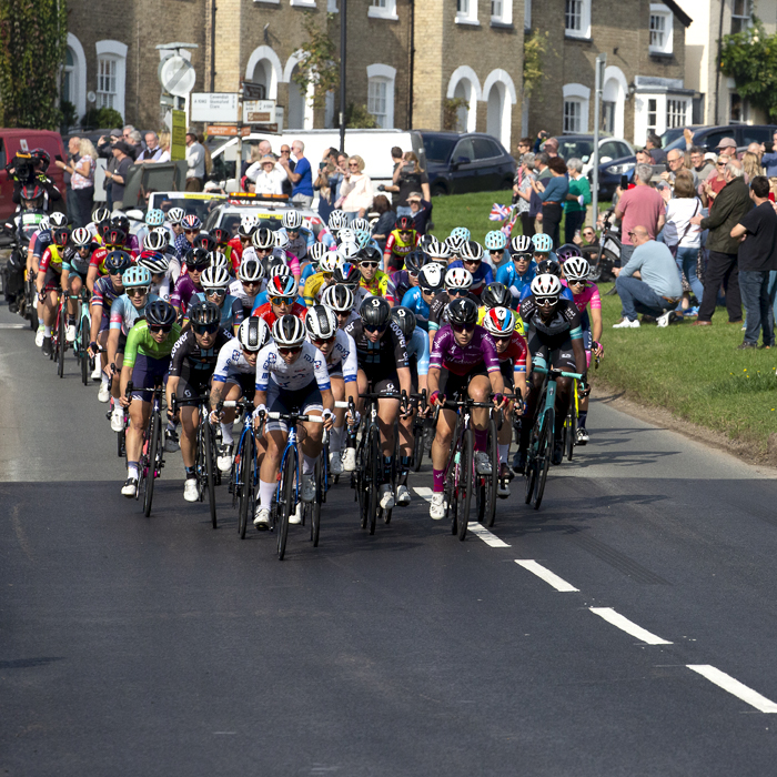 Women’s Tour 2021 - The peloton passes by the village green in Long Melford