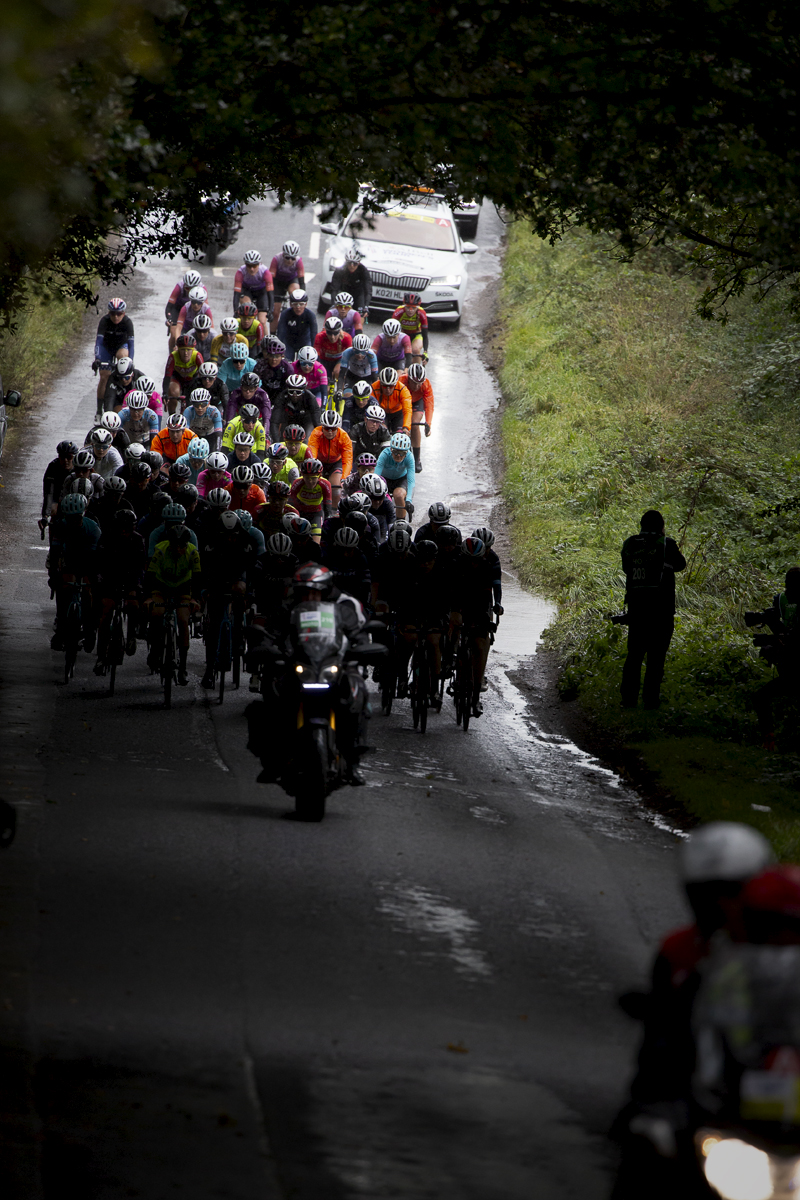 Women’s Tour 2021 - The peloton is silhouetted on wet tree lined roads